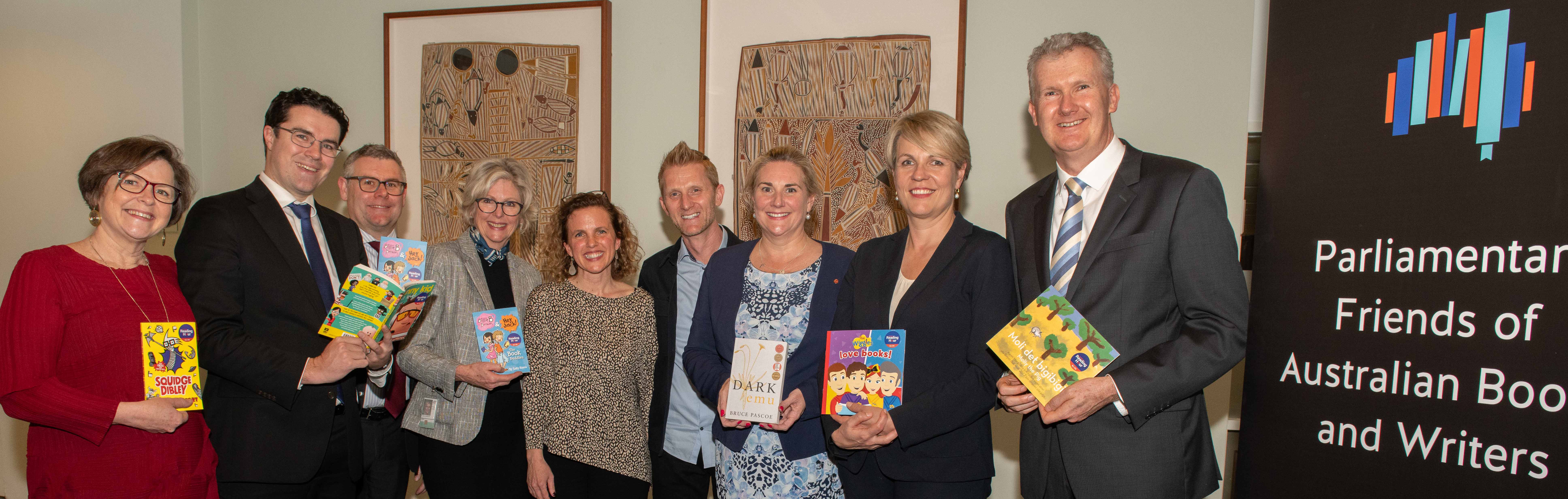 Politicians holding books by a Parliamentary Friends of Australian Books and Writers banner